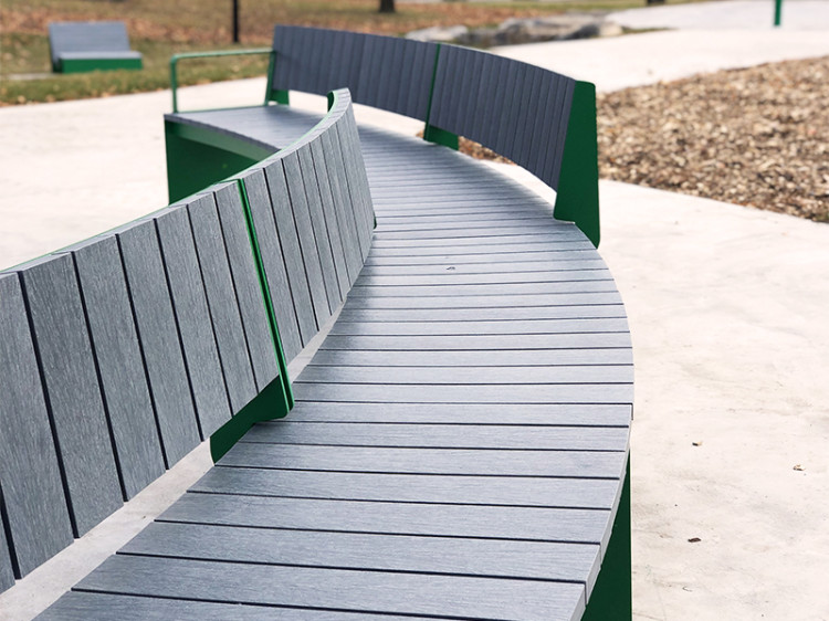 Banc en arc de cercle dans un contexte de parc urbain. Mobilier urbain.