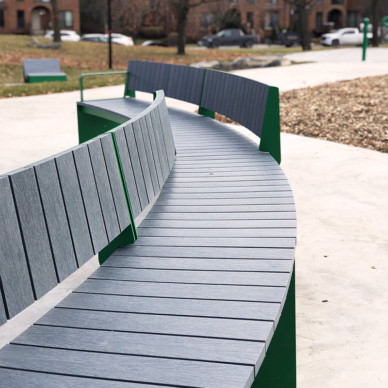 Banc en arc de cercle dans un contexte de parc urbain. Mobilier urbain.